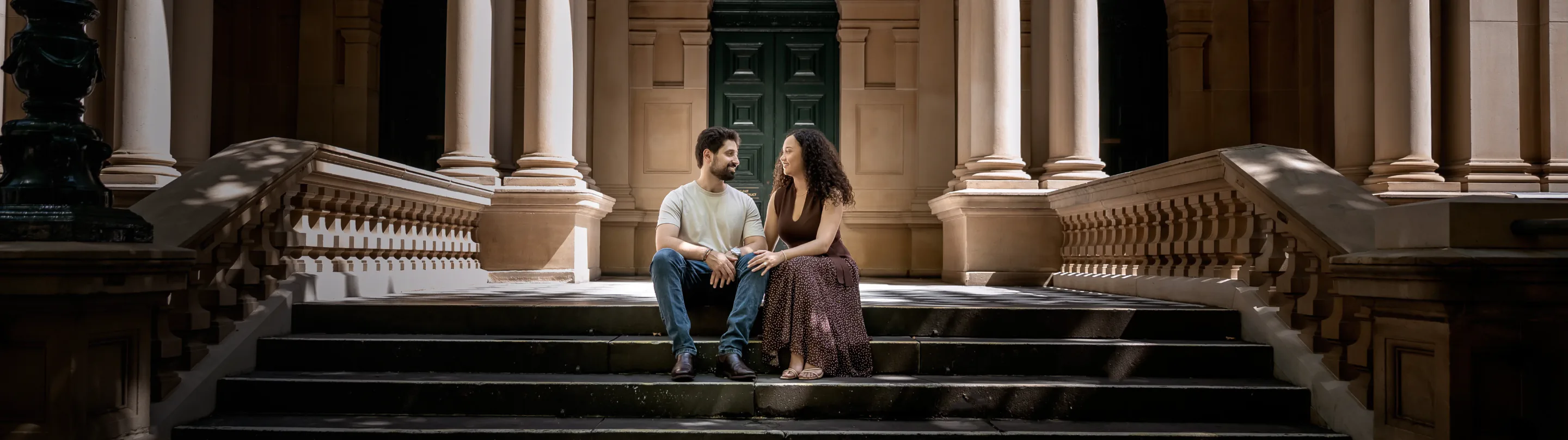 Couple sitting on sandstone steps in a colonnade