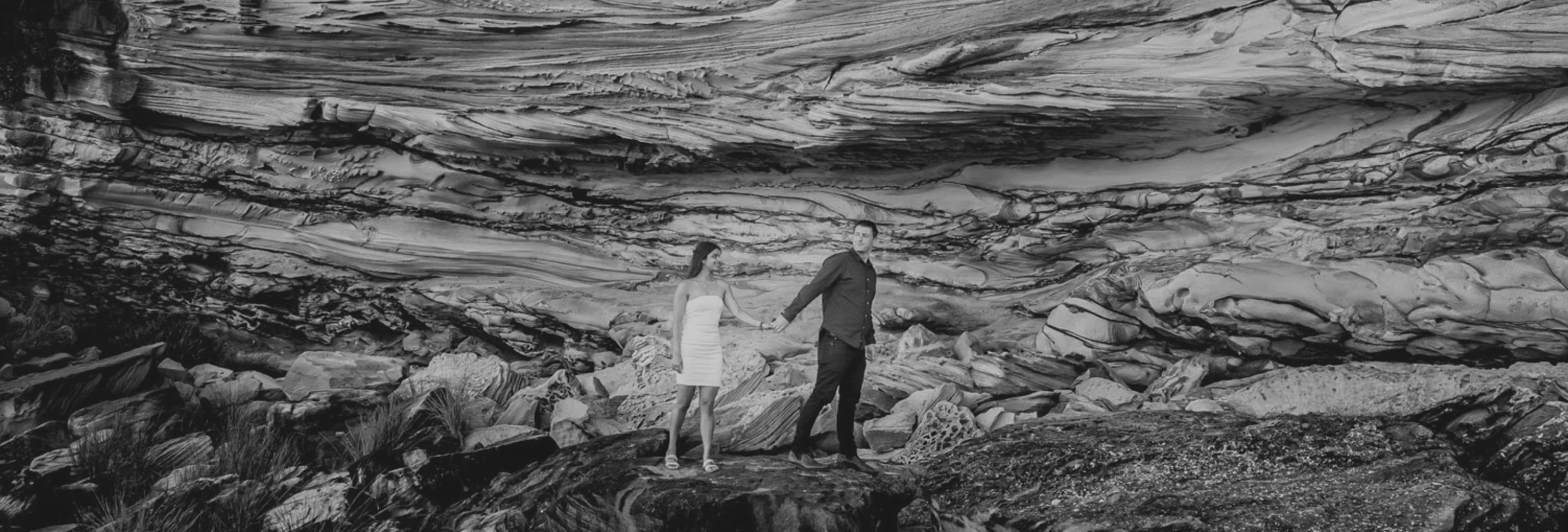 Couple holding hands on layered sandstone rock