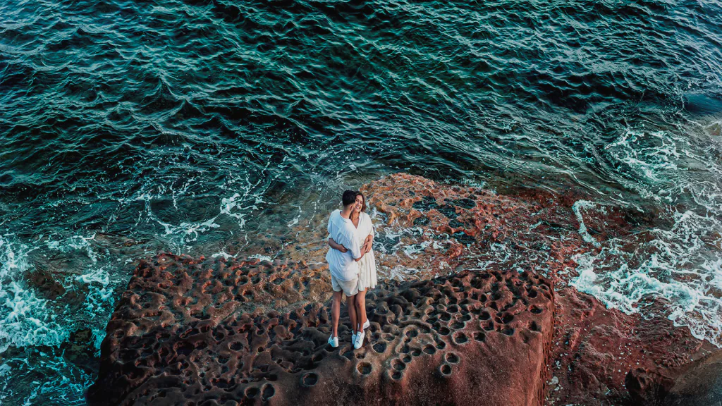 Couple embracing on coastal rocks by the ocean