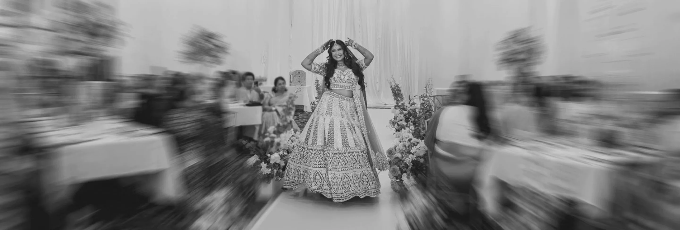 Bride walking an aisle in a lehenga during a Grand House wedding