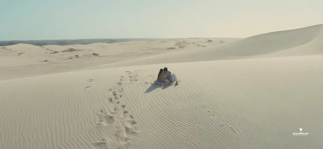 Aerial view of a couple sitting on sand dunes