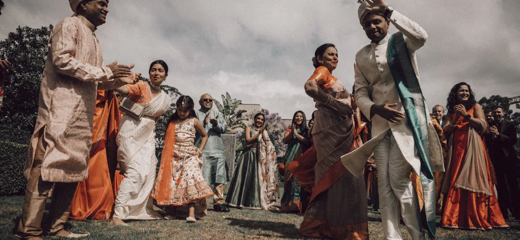 Wedding guests in traditional Indian attire dancing and celebrating outdoors